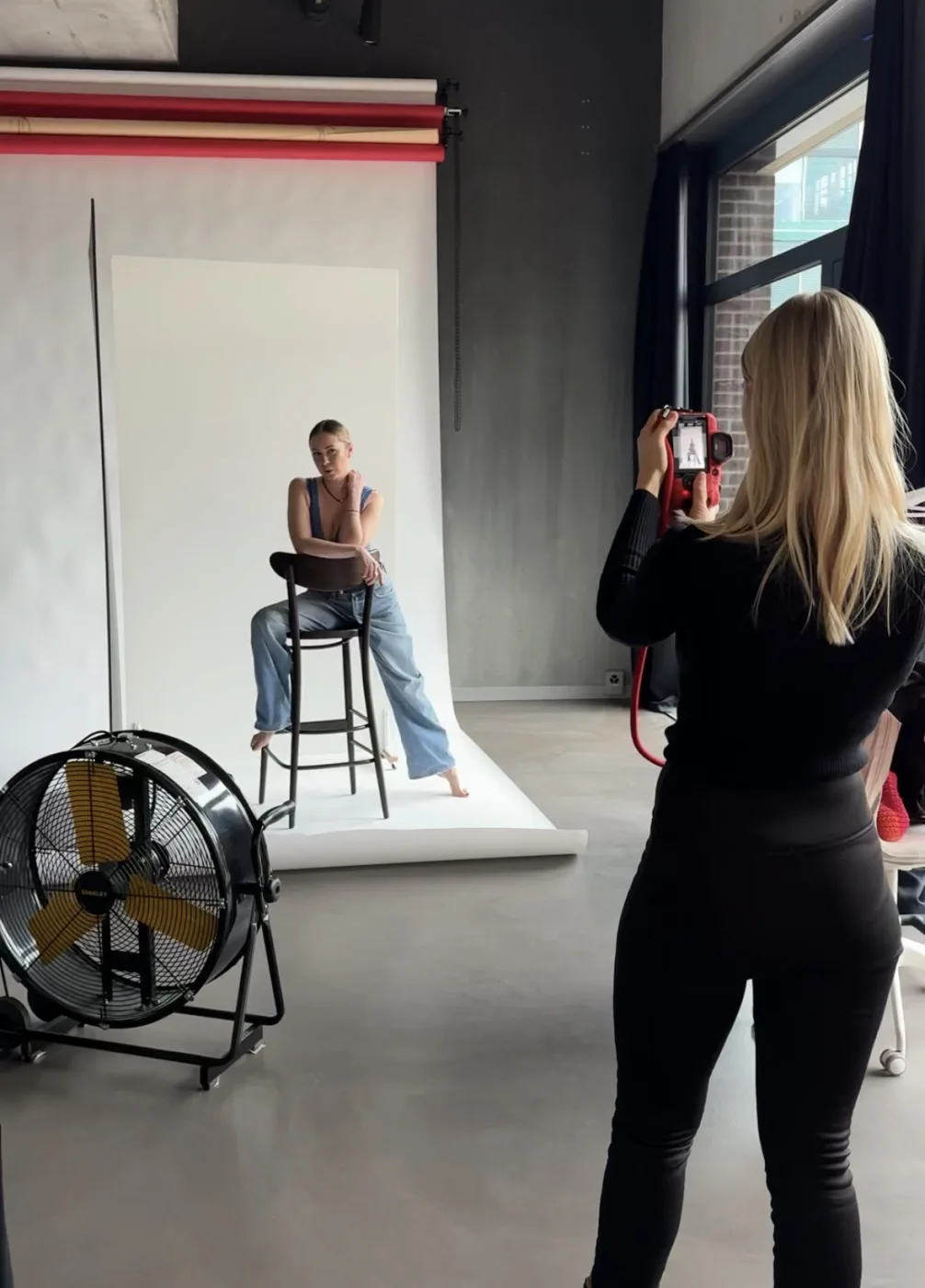 Fotografin fotografiert ein Model vor weisser Hintergrundrolle im dibe Studio.