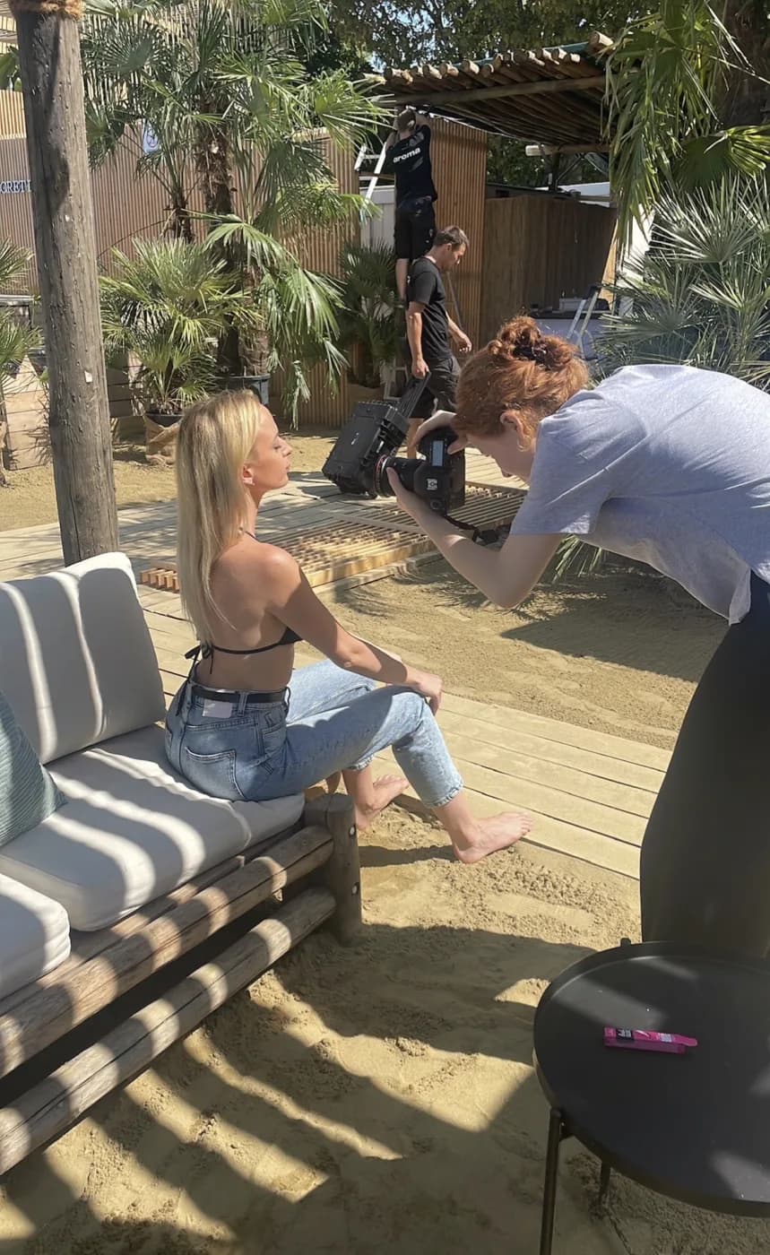 Outdoor-Shooting am Strand: Fotografin fotografiert ein Model auf einer Lounge im Sand.