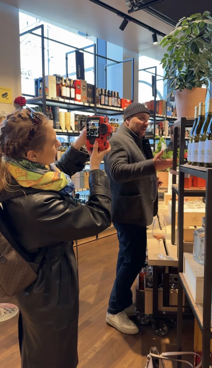 Content-Produktion im Ladenlokal: Aufnahme mit roter Kamera zwischen Weinregalen.